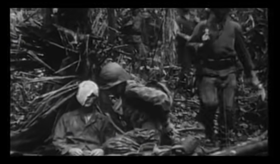 A marine raider medic applied a bandage on the face of a wounded fellow sitting in the forest