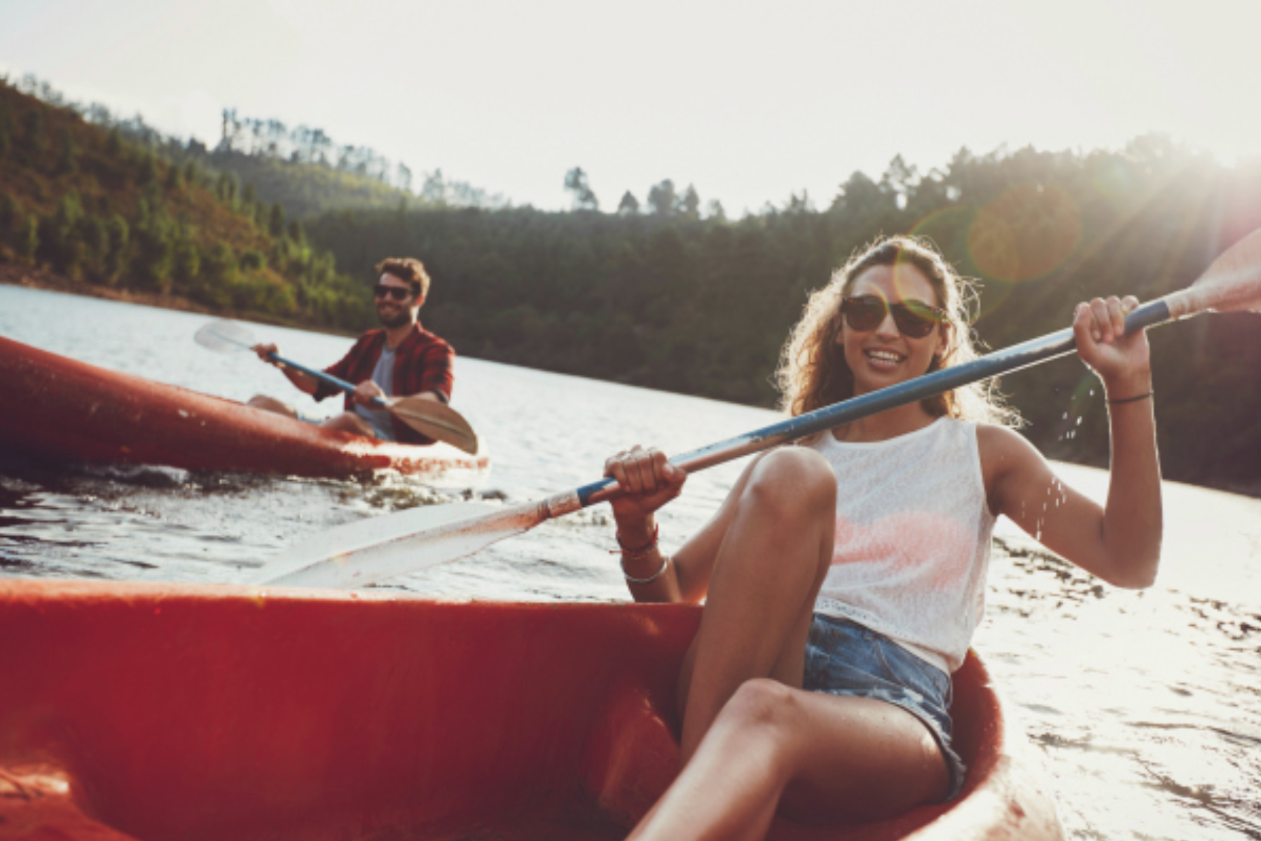 A guy and a woman paddle a little red kayak
