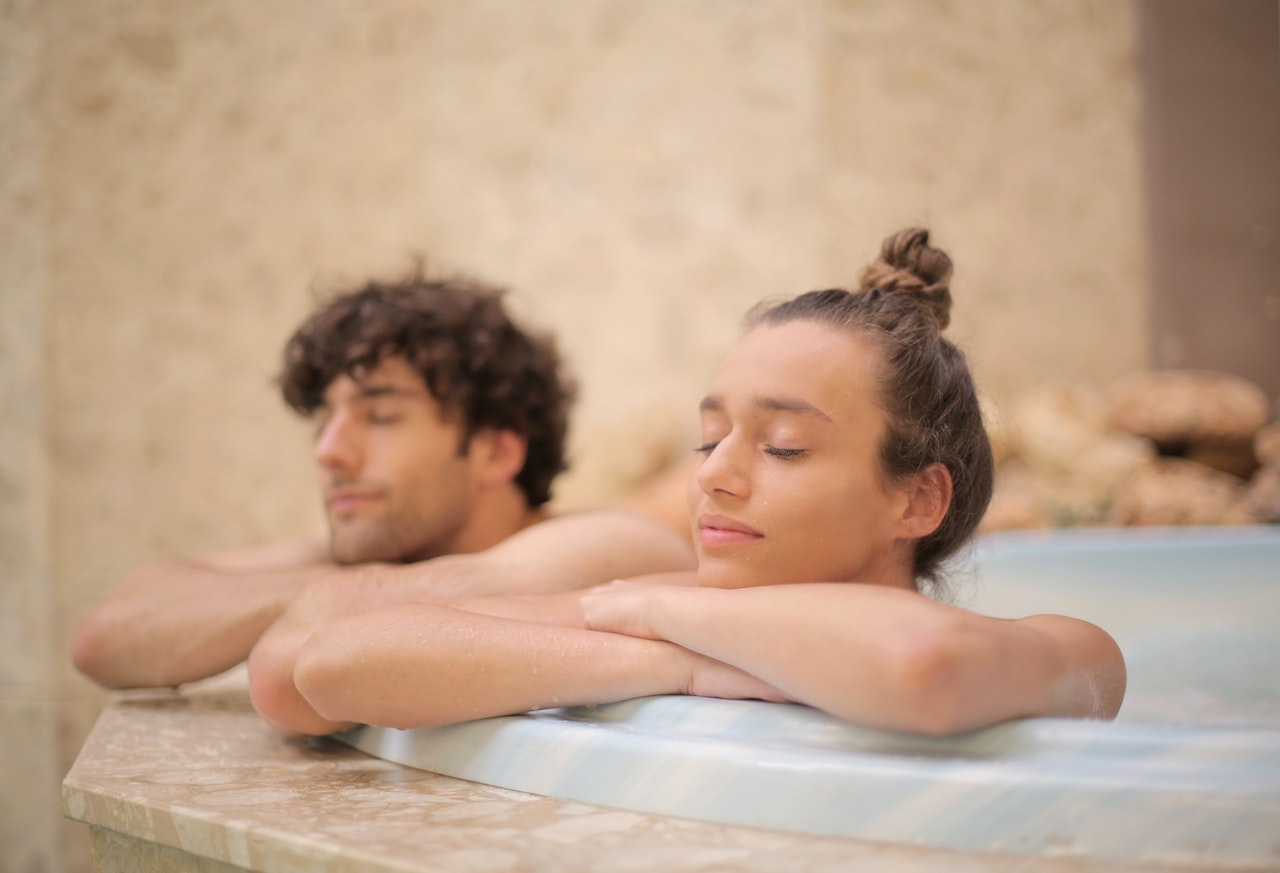 Young satisfied couple relaxing at spa bathtub during vacation