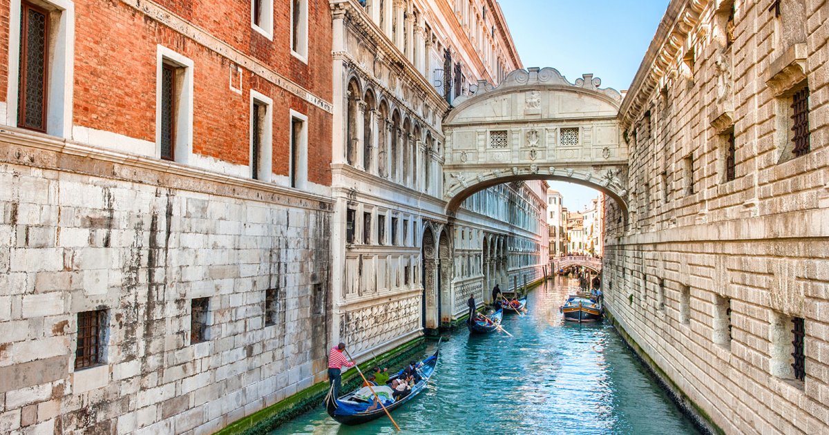 People rowing boats in a canal at Doge's Palace And Bridge Of Sighs