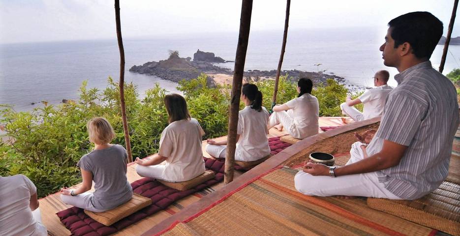 Men and women doing meditation overlooking an ocean view