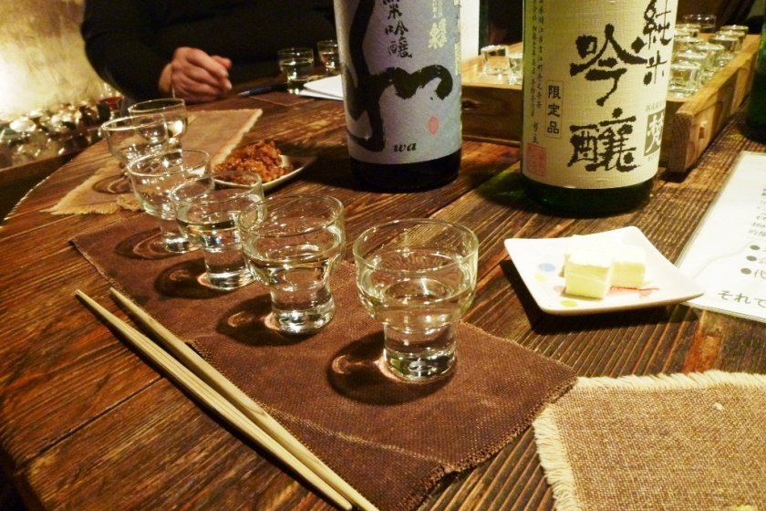 Sake and many small glasses on the wooden table.