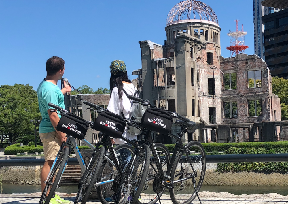 A man and a woman on the Hiroshima Cycling Peace Park with their bicycles.
