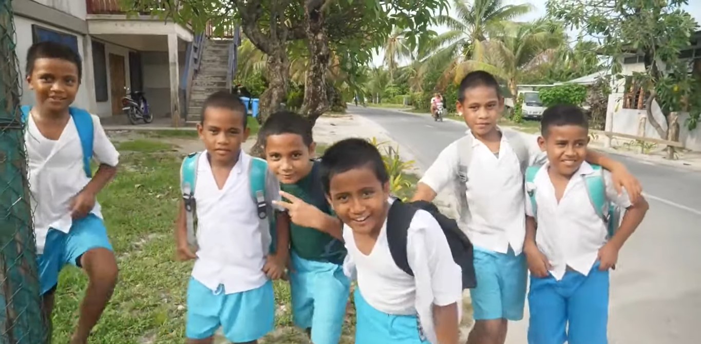 Six male Tuvalu children along the street in their school uniform of white polo and sky-blue shorts